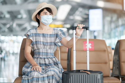 Woman wearing mask sitting at airport