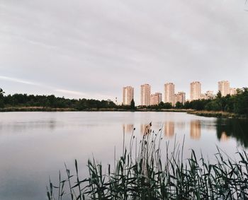 Scenic view of lake by cityscape against sky