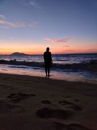 Silhouette man standing on beach during sunset