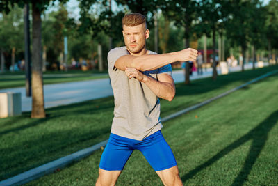 Portrait of young man exercising on field