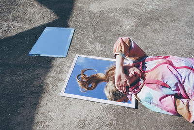 Woman shielding eyes from sunlight lying down on mirror