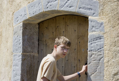 Portrait of teenager holding door handle