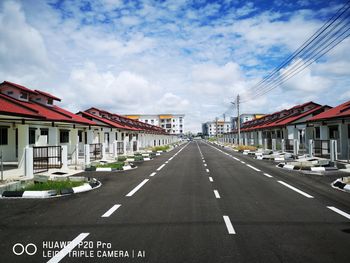 Empty road by buildings against sky