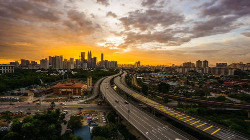 High angle view of city street and buildings against sky during sunset