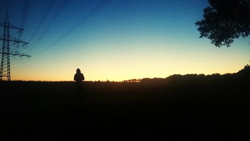 Silhouette trees on field at sunset