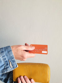 Close-up of hand holding paper against white background