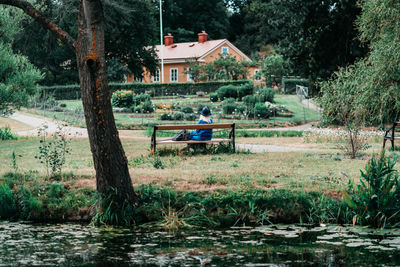 Houses by lake and trees against sky