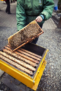 Midsection of beekeeper with beehive