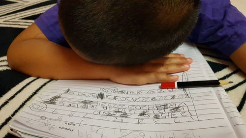 High angle view of boy reading book on table