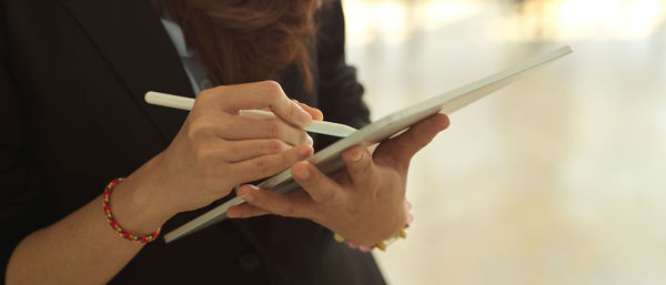 Midsection of woman using digital tablet