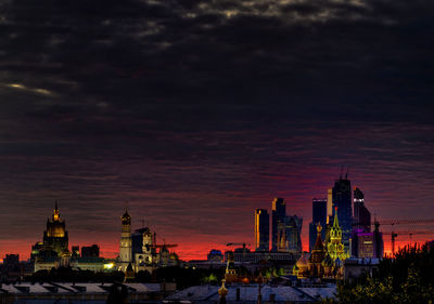 Illuminated buildings in city at sunset