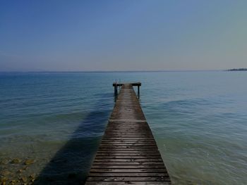 Wooden jetty in sea against clear sky