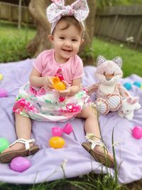 Cute girl with toy sitting outdoors