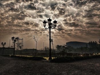 Silhouette street light on field against sky during sunset