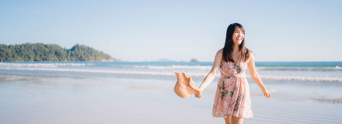 Woman standing at beach against sky