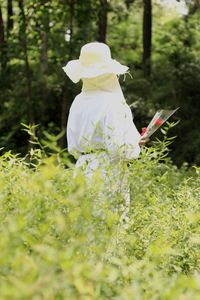 Rear view of woman with white flowers on field