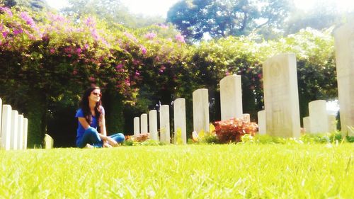 Young woman sitting on grassy field at kirkee war cemetery