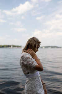 Woman standing by lake against sky