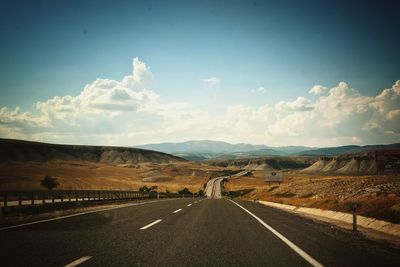 Empty road along landscape against sky