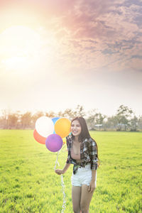 Full length of a smiling young woman standing on field