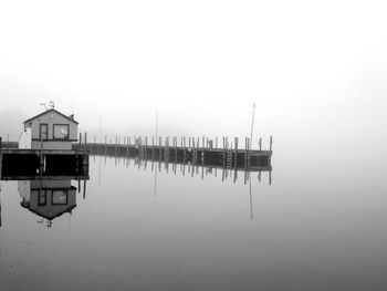 Wooden posts in lake against sky