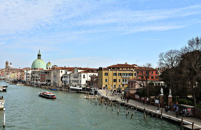 Canal amidst buildings in city against sky