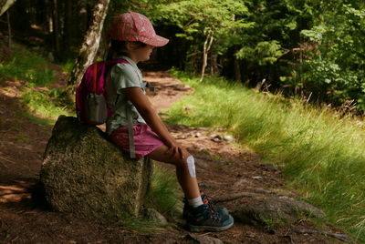 Side view of young woman sitting on field