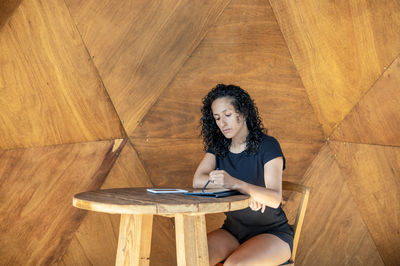 Woman using a digital tablet while sitting at a table.