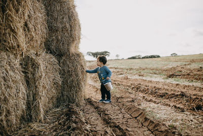 Side view child with bucket playing with hay