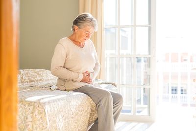 Senior woman sitting on bed at home