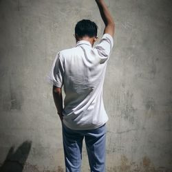 Rear view of boy standing against wall