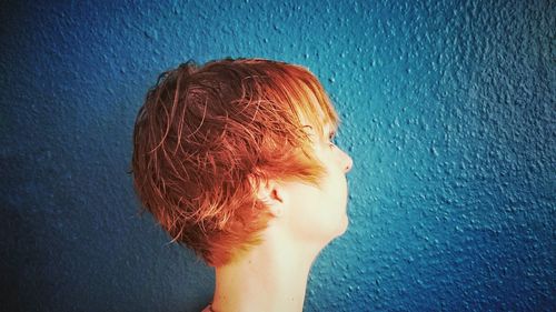 Close-up of woman with short hair against wall