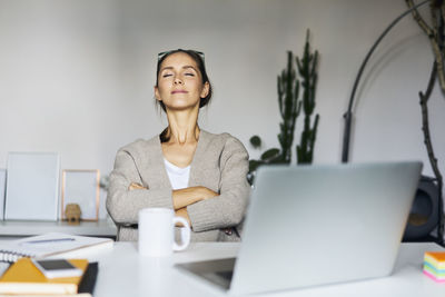 Young woman at home with laptop on desk having a break