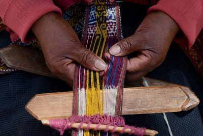 Midsection of person weaving textile in factory