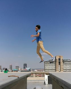 Boy jumping against clear blue sky