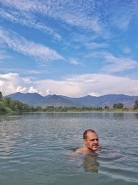 Portrait of shirtless man in lake against sky