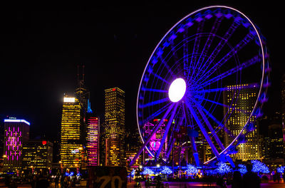 Illuminated ferris wheel against sky at night