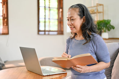 Young woman using digital tablet while sitting on table