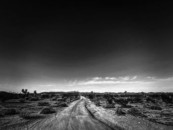 Road amidst field against sky