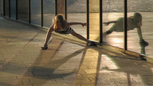 Full length portrait of girl dancing with reflection on glass