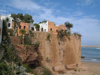 Buildings by beach against cloudy sky