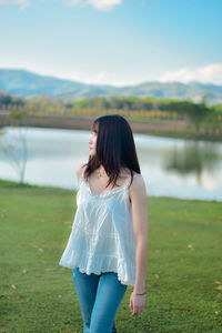 Rear view of woman standing against lake