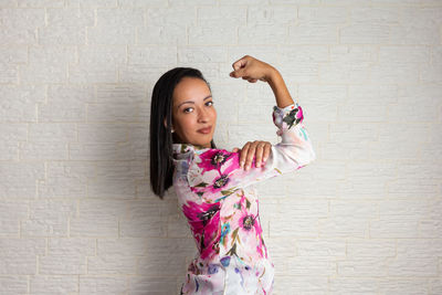 Portrait of young woman standing against wall