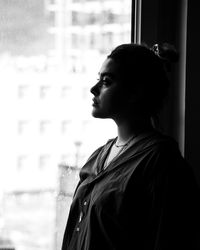 Side view of young woman looking through window