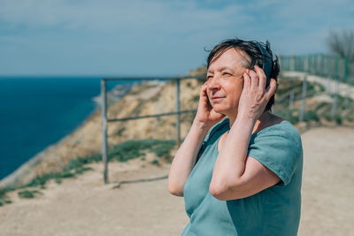 Portrait adult woman listens to music in headphones in summer, spring against the backdrop of