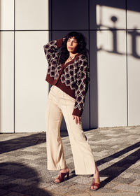 Full length of young woman standing against wall