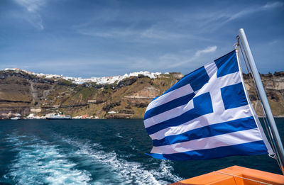 Flag by sea against blue sky