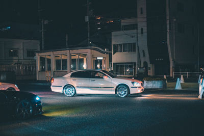 Cars on road by buildings in city at night