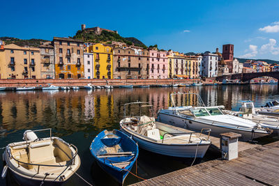 Boats moored at harbor against buildings in city