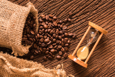 High angle view of roasted coffee beans and hourglass on wooden table